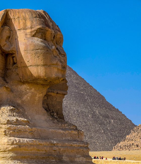 The Great Sphinx of Giza in front of the Great Pyramid under a deep blue sky