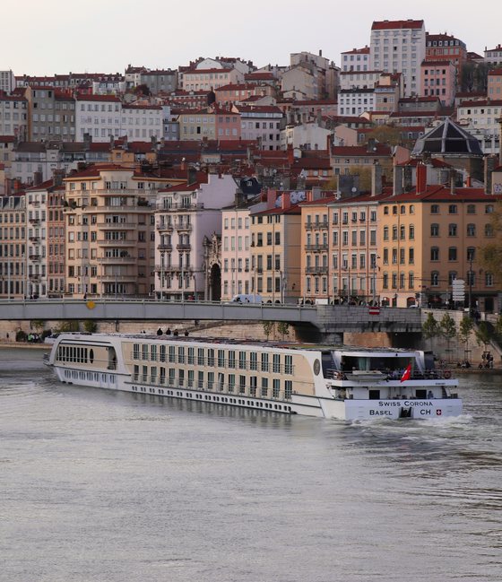 River cruise ship gliding past colorful riverside buildings in a European city