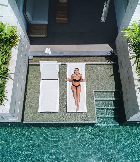Overhead view of a woman relaxing on a lounger in a swim-up suite pool at an all-inclusive resort